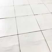 Angled close up view of a group of matte 5x5 textured powder white tiles showing the textured edges.