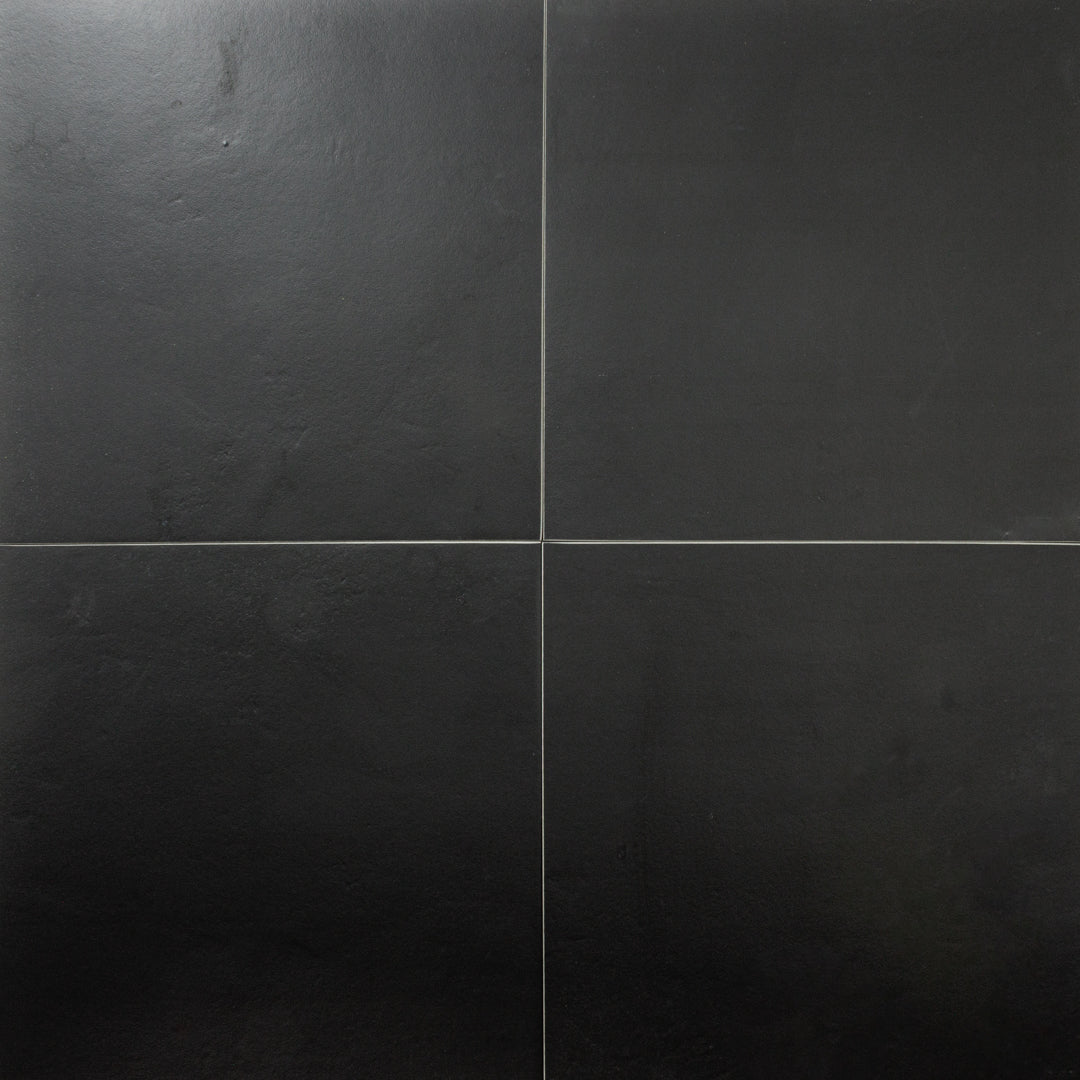 An aerial view of four black 12x12 tiles together in a square. The tiles feature a stone look with subtle texture and a matte finish.  An aerial view of four black 12x12 tiles together in a square. The tiles feature a stone look with subtle texture and a matte finish.