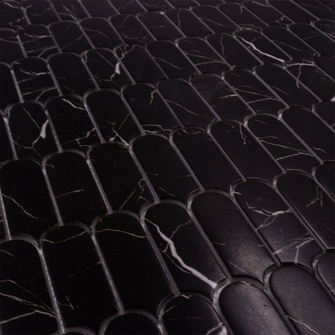 Angled close up of black marquina marble look feather scallop mosaic sheet tiles to show the pattern and finish. 