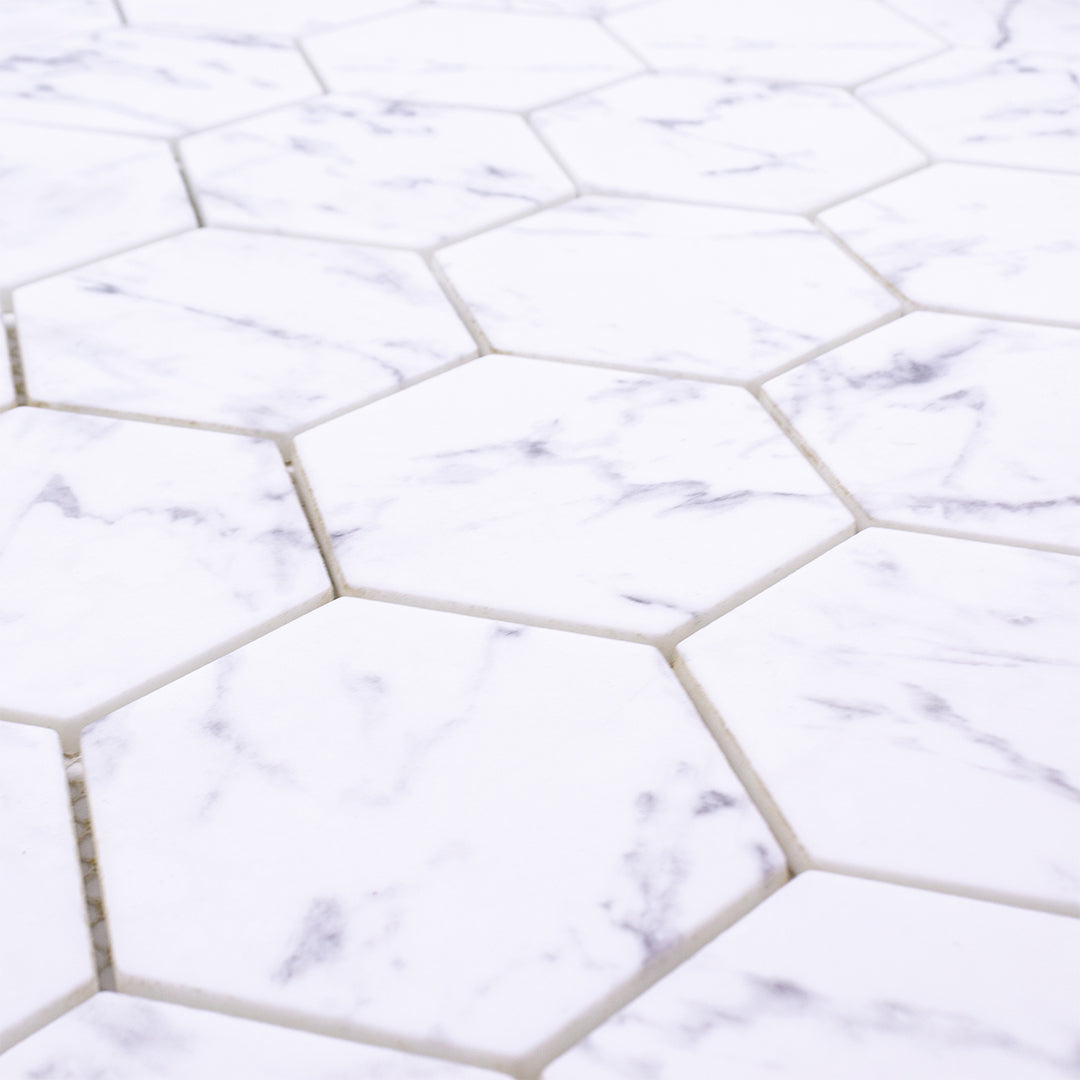 Angled close up of 3 inch hexagon Carrara look recycled glass mosaic tiles. 