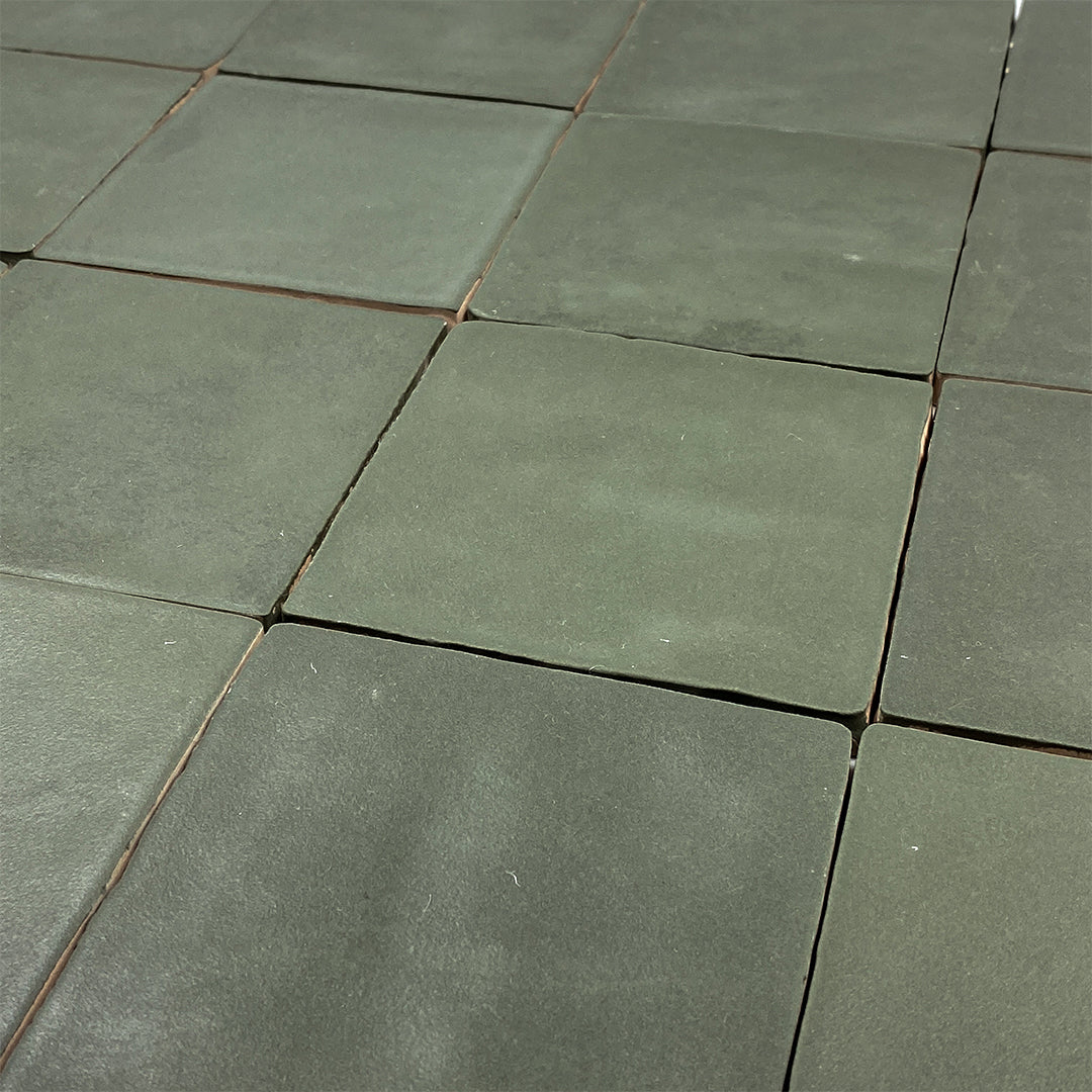 Angled close up of a group of 4x4 satin zellige tiles named hearth olive green. they have a handmade look, textured edge and a subtle colour variation