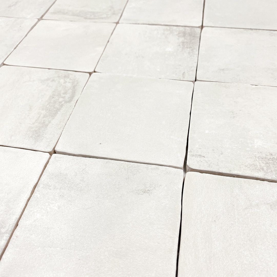 Angled close up of a group of 4x4 satin zellige tiles named plaster off white. they have a handmade look a subtle colour variation