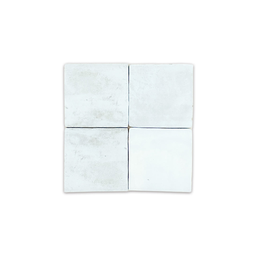 ariel view of a group of four 4x4 satin zellige tiles named hearth sky blue. they have a handmade look, textured edge and a pale blue colour variation
