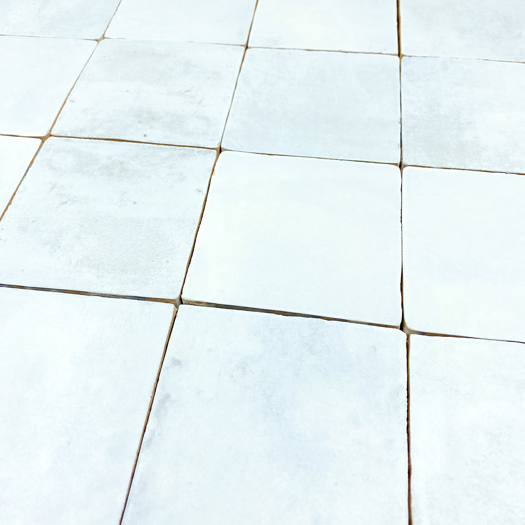 Angled ariel view of a group of 4x4 satin zellige tiles named hearth sky blue. they have a handmade look, textured edge and a pale blue colour variation