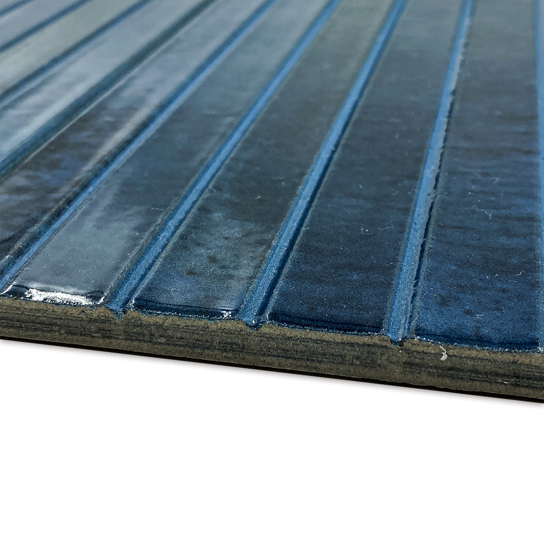 Angled close up view of a single 5x10 panel tile in glossy navy blue, the tile has a 3D linear faux grout line kitkat look. This angle highlights the depth and texture of the reeds. 