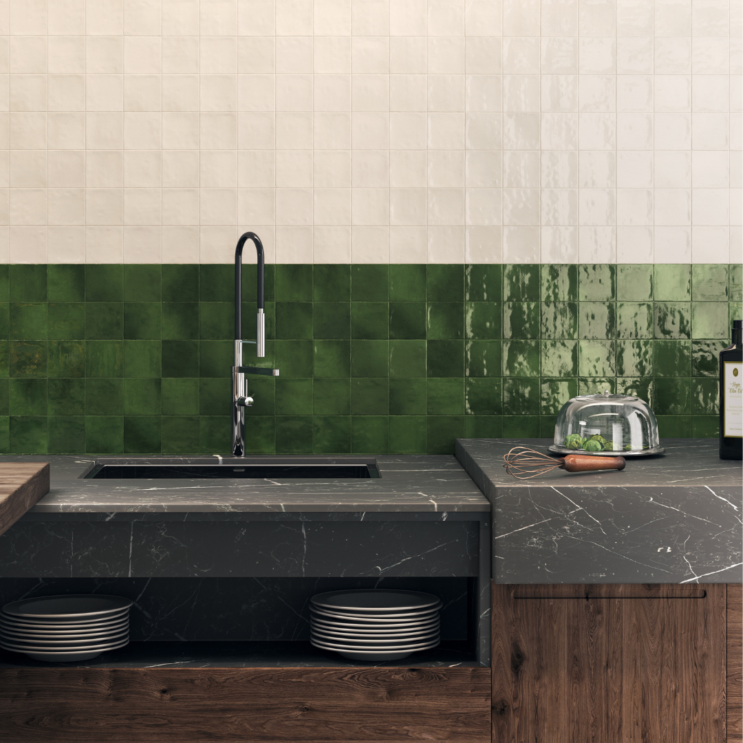 A minimalist kitchen with wood cabinets and a black counter top featuring an interesting backsplash. The lower section of backsplash against the counter is 4x4 glossy textured green tiles and above those tiles are 4x4 glossy textured ivory tiles. 