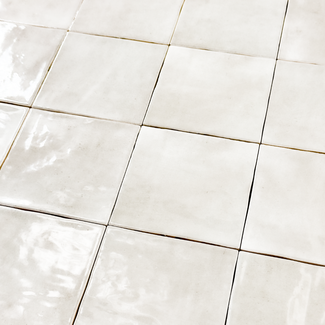 Angled ariel view of a group of glossy 4x4 grey tiles. Highlighting the slight colour variations, texture and finish.