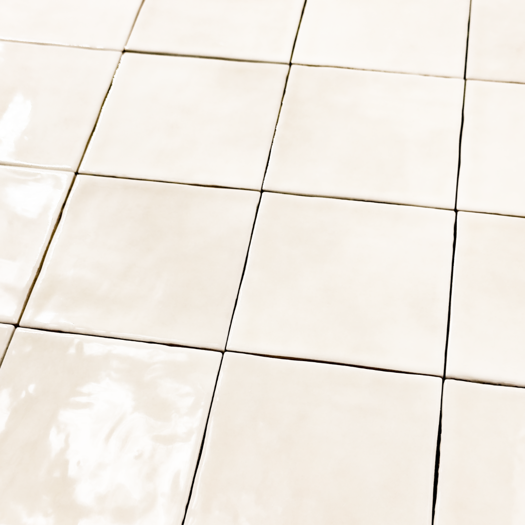 Angled ariel view of a group of glossy 4x4 textured ivory tiles showing the colour and texture. 