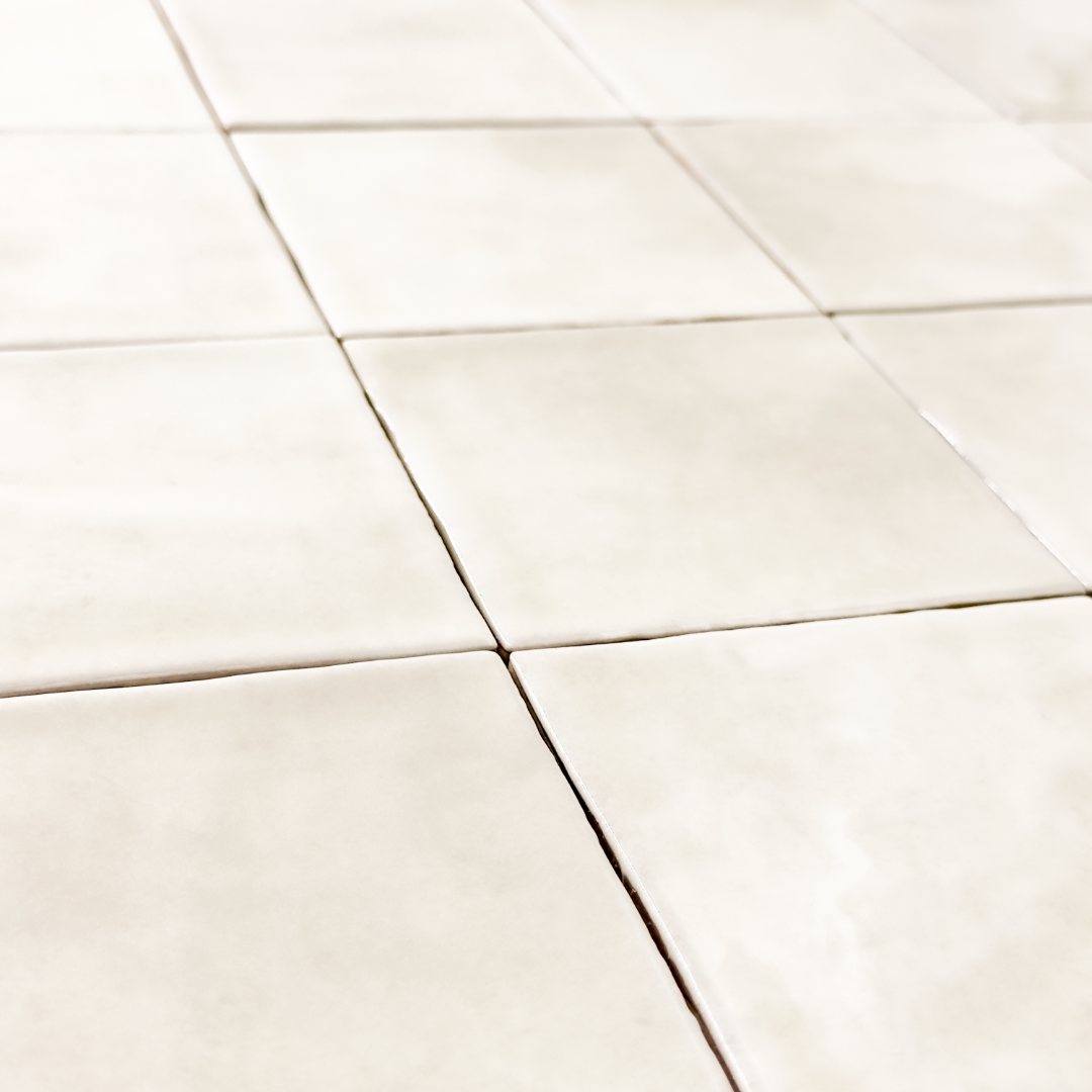 Angled close up view of a group of glossy 4x4 textured ivory tiles showing the colour and texture. 