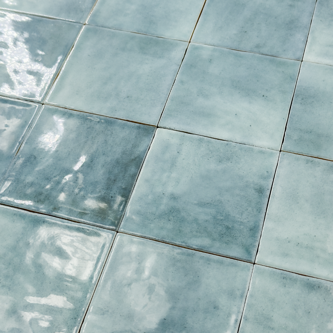 Angled ariel view of glossy 4x4 textured light denim blue tiles showing the colour and texture. 