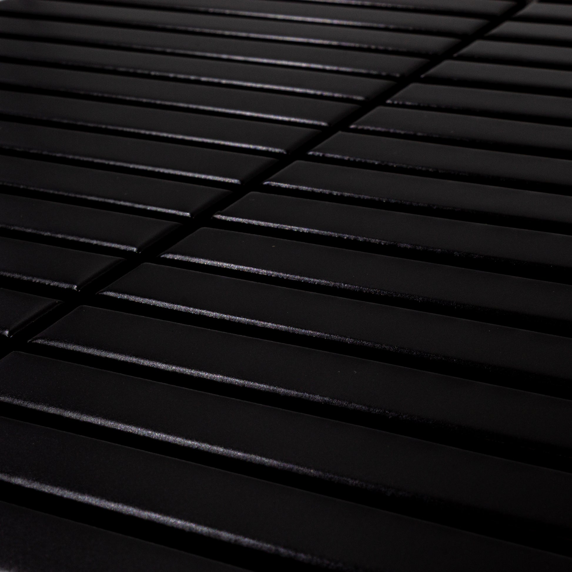 Angled close up view of a single sheet of kitkat stacked mosaic tiles in matte true black. The sizing is 5/8' x 5-5/8" per tile, 11" X 12" per sheet