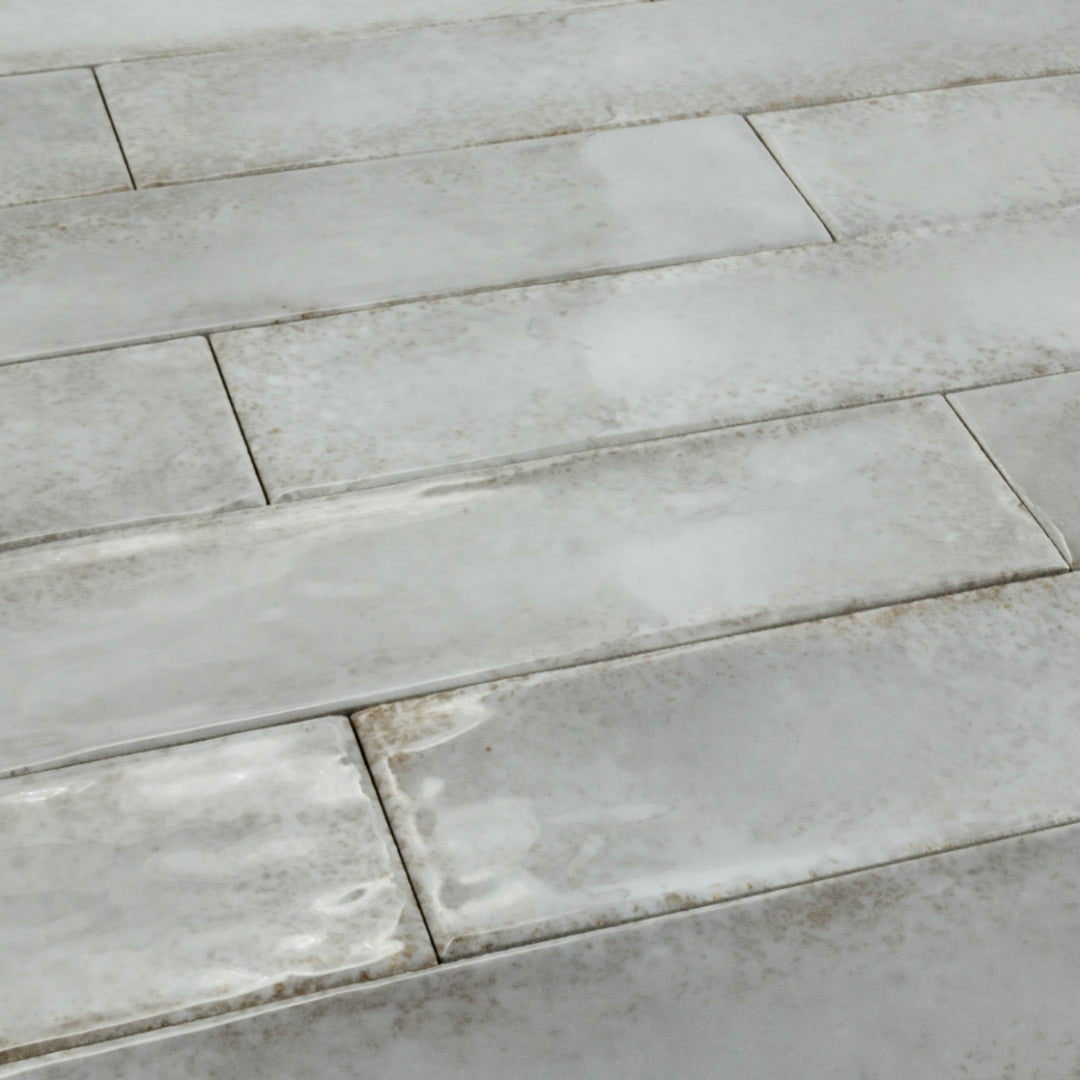Angled close up of 2x9 grey rustic glossy tiles in a brick layout