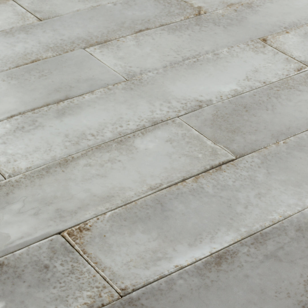 Angled close up of 2x9 gray rustic handmade look glossy tiles in a brick layout