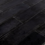 Angled close up of 2x9 black glossy tiles in a brick layout