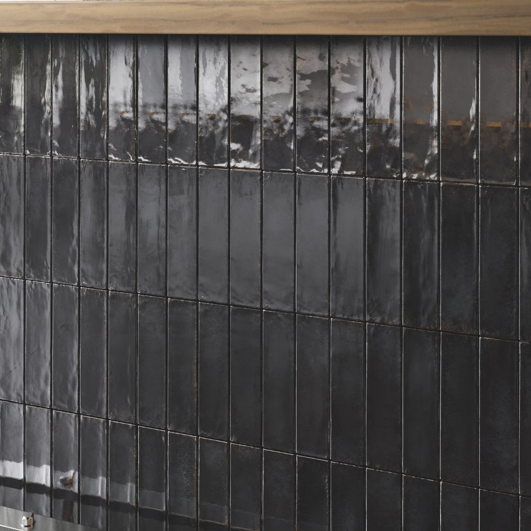 A modern backsplash zoomed in to highlight the black 2x9 glossy backsplash tiles. They are in a modern vertical stack layout. 