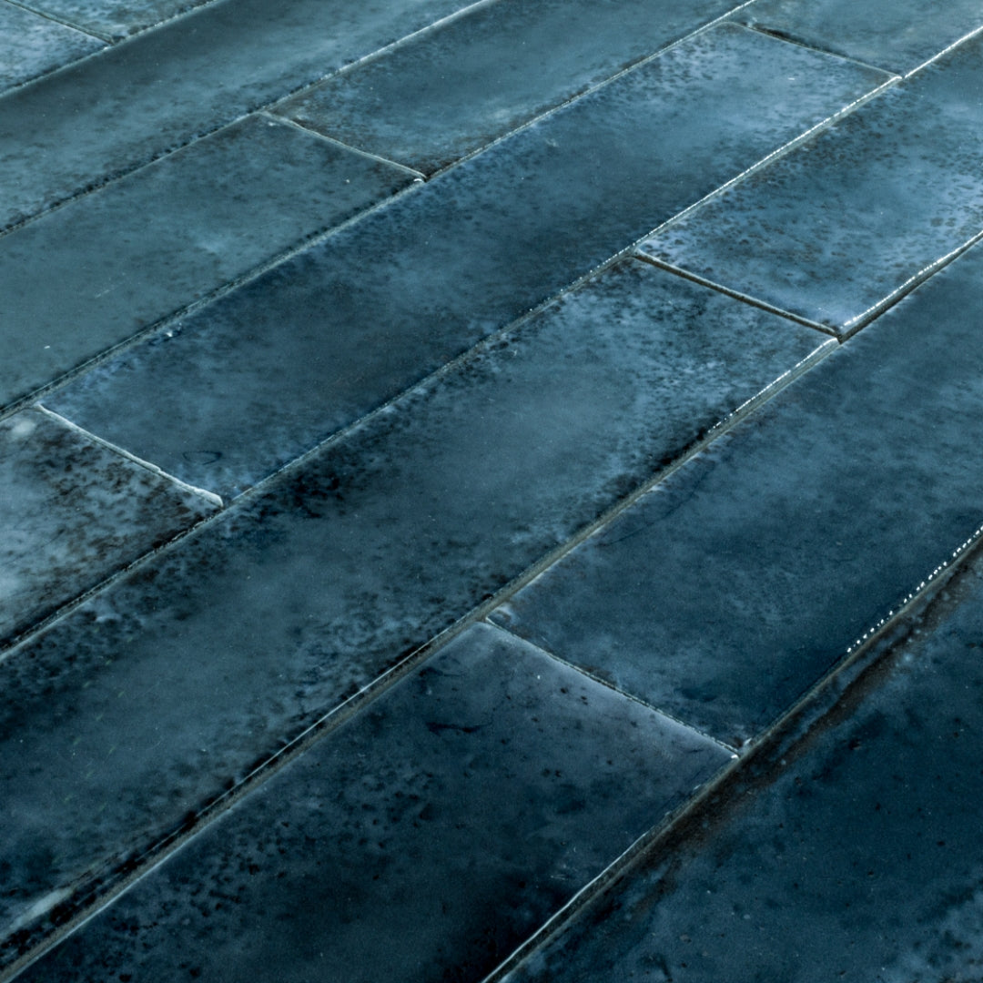 Angled close up of 2x9 blue glossy tiles in a brick layout