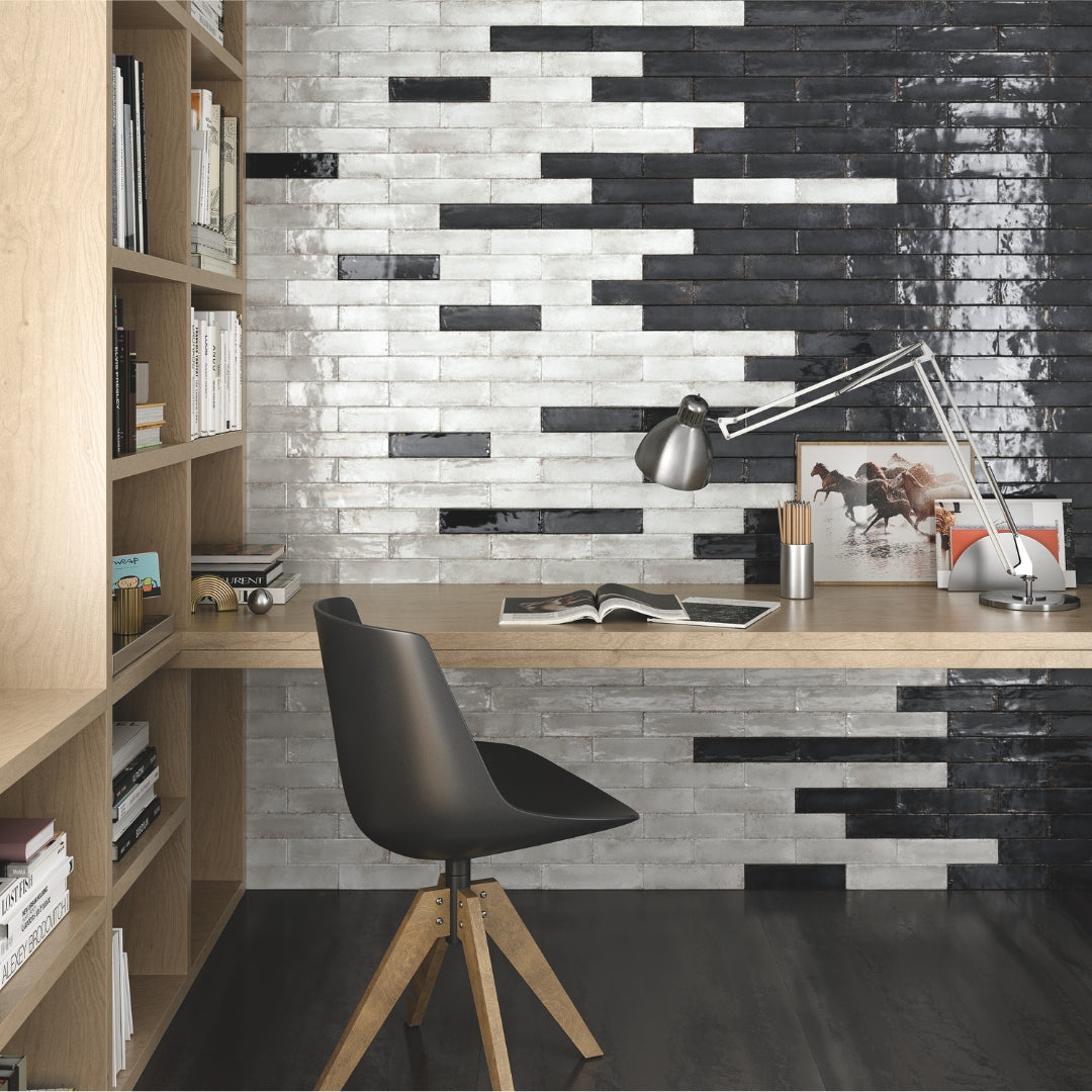 A feature wall behind a desk using black and white 2x9 glossy tiles. There is a 50/50 mix of each in a brick layout. 
