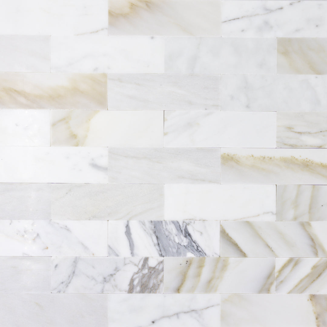 a random group of matte calacatta 2x6.5 subway tiles laid in a brick pattern
