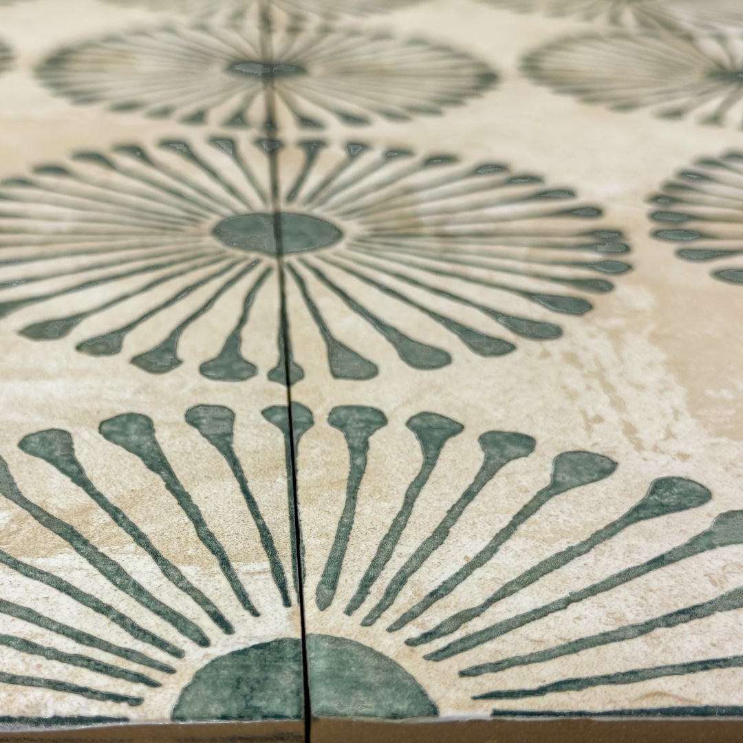 Angled view of the miramar green highlighting the finish and green sunburst pattern on the gray backgrount tile. 