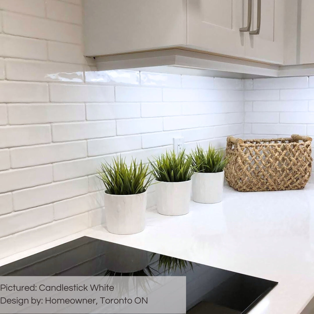 A close up on a simple white kitchen backsplash using 2x10 candlestick white glossy tiles in a traditional brick layout. 
