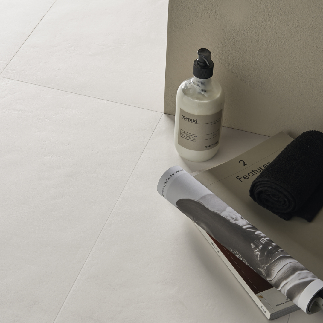 Close up detailed photo of the 12x24 white tile in a spa area with a magazine, bottle of lotion and a towel. 