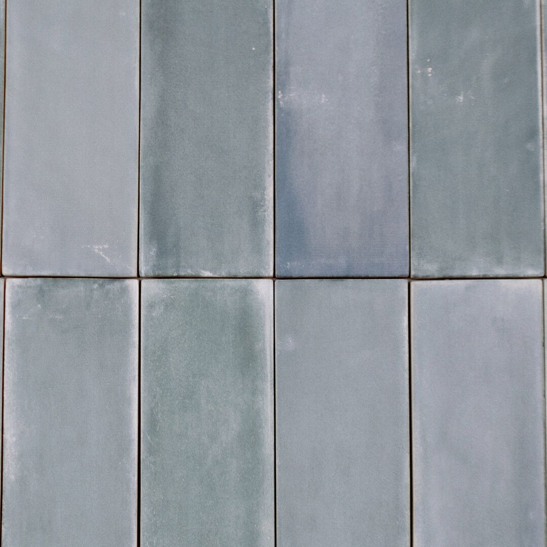Ariel close up of eight 2x6.5 matte basalt cool toned gray subway tiles to show the colour variations. 