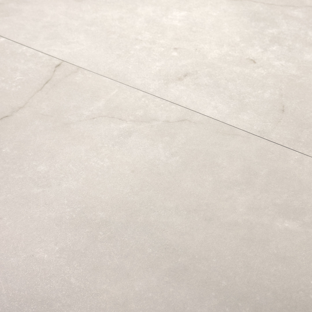 Angled close up of two 12x24 creamy white avorio marble look tiles with thin veining and a light pattern. 