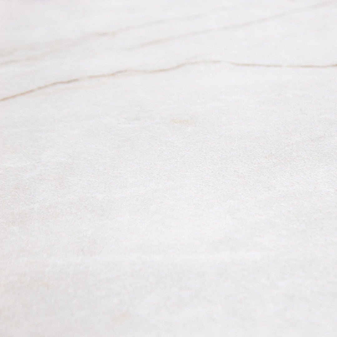 A close up view of a 24x48 marble look bianco white tile with thin grey veining highlighting the colour and matte texture. 