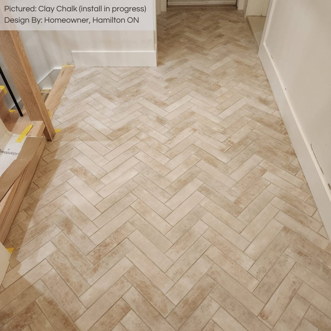 An upper floor hallway with light wooden stairs and white walls. The floors are 11x2.75 clay chalk white terracotta look brick tiles laid out in a herringbone for a charming natural look. there is beige and creamy tones in the tiles variations. 