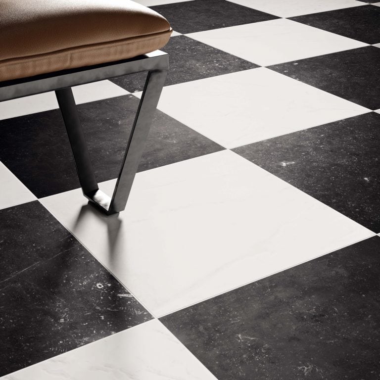 Angled close up view of a floor installation using 16x16 matte marble stone look black and white tiles. 