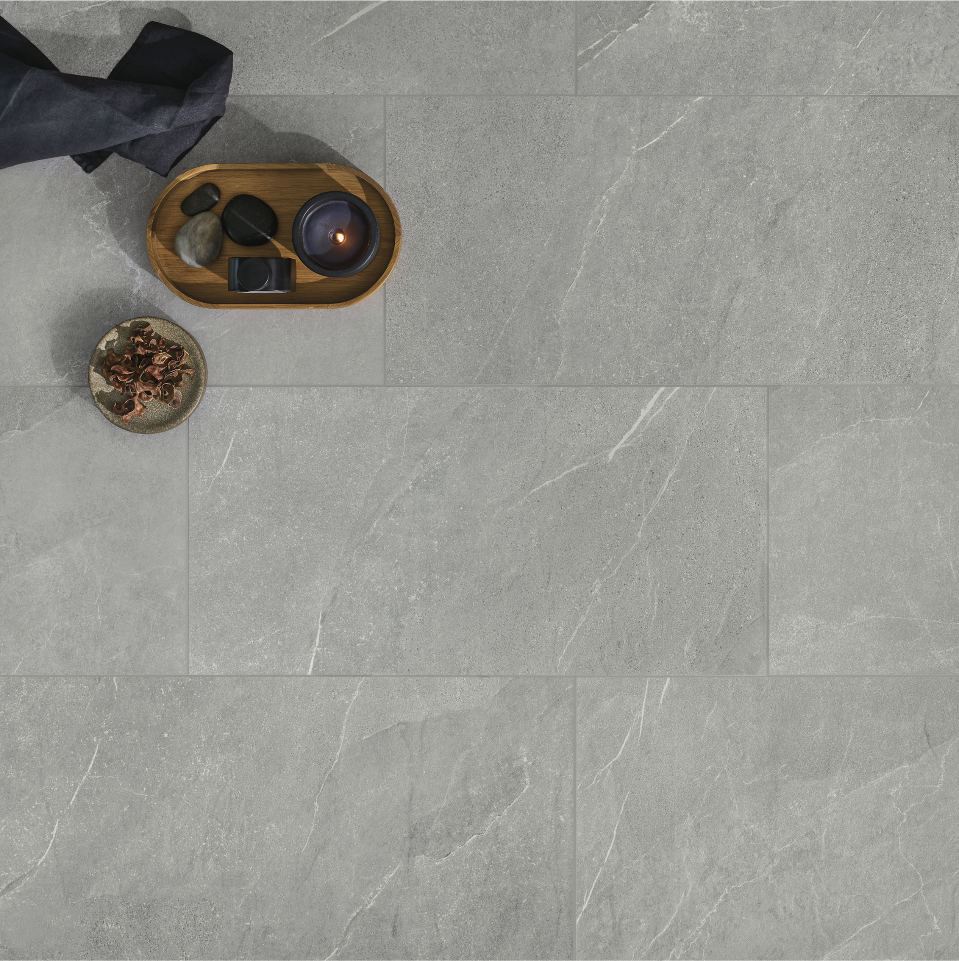 Ariel view of a floor setting with candles and natural elements decor. The tile flooring is a large scale limestone look dark grey tile with soft delicate veining. 