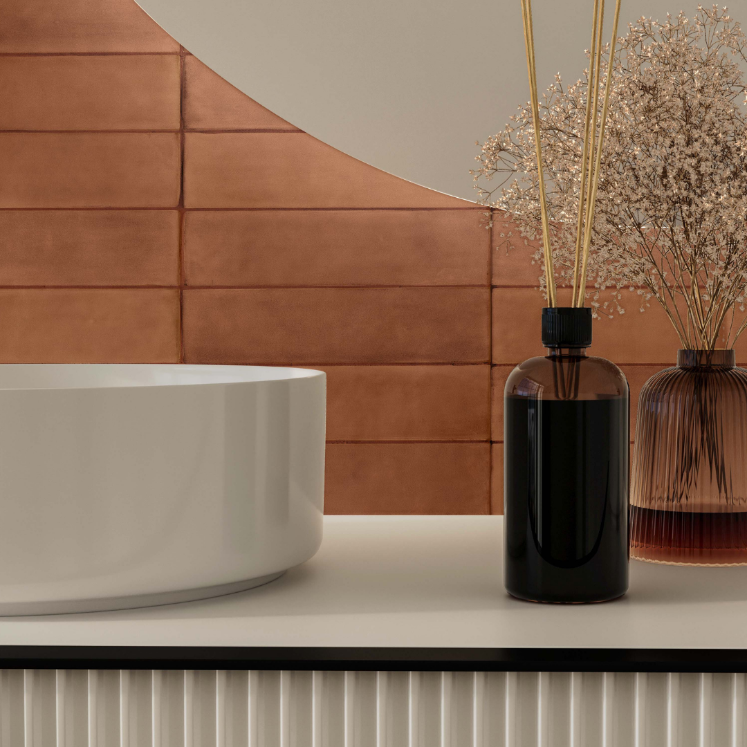 Close up of a bathroom vanity tile backsplash featuring a 2x9 terracotta coloured matte subway tile. The tile has colour variation and a soft texture appearance. The white fixtures pop against the orange tile. 