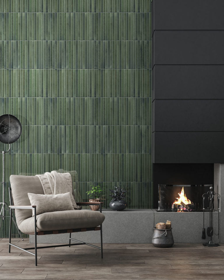 A modern living room with a black fireplace and grey decor. The tiled wall in the backdrop is green keys 5x10 fluted kitkat tiles. They have an earthy colour variation. 