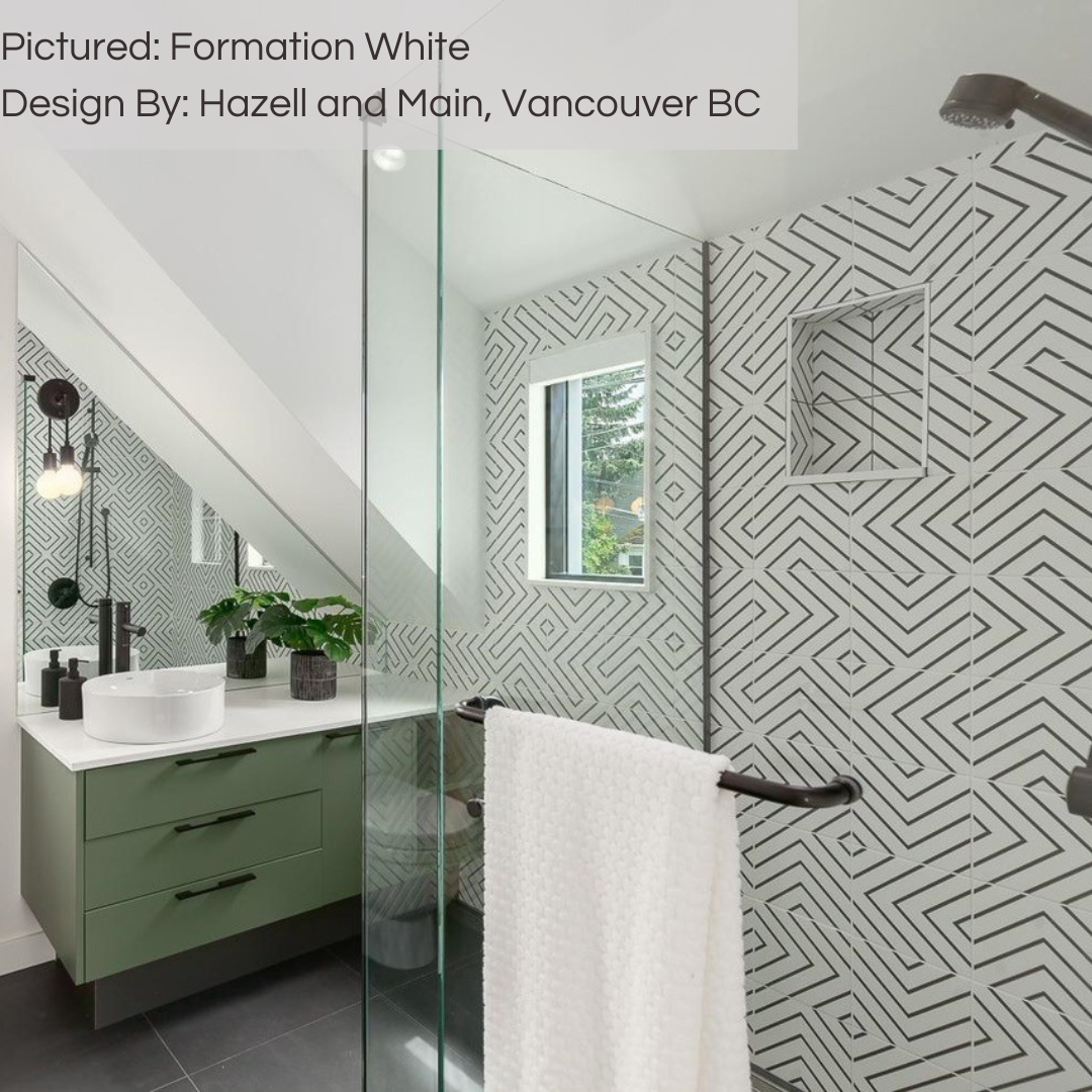 A modern and fun accent wall in a bathroom using formation white geometric pattern 8x8 tiles. black finishes, white painted walls and a green vanity. 