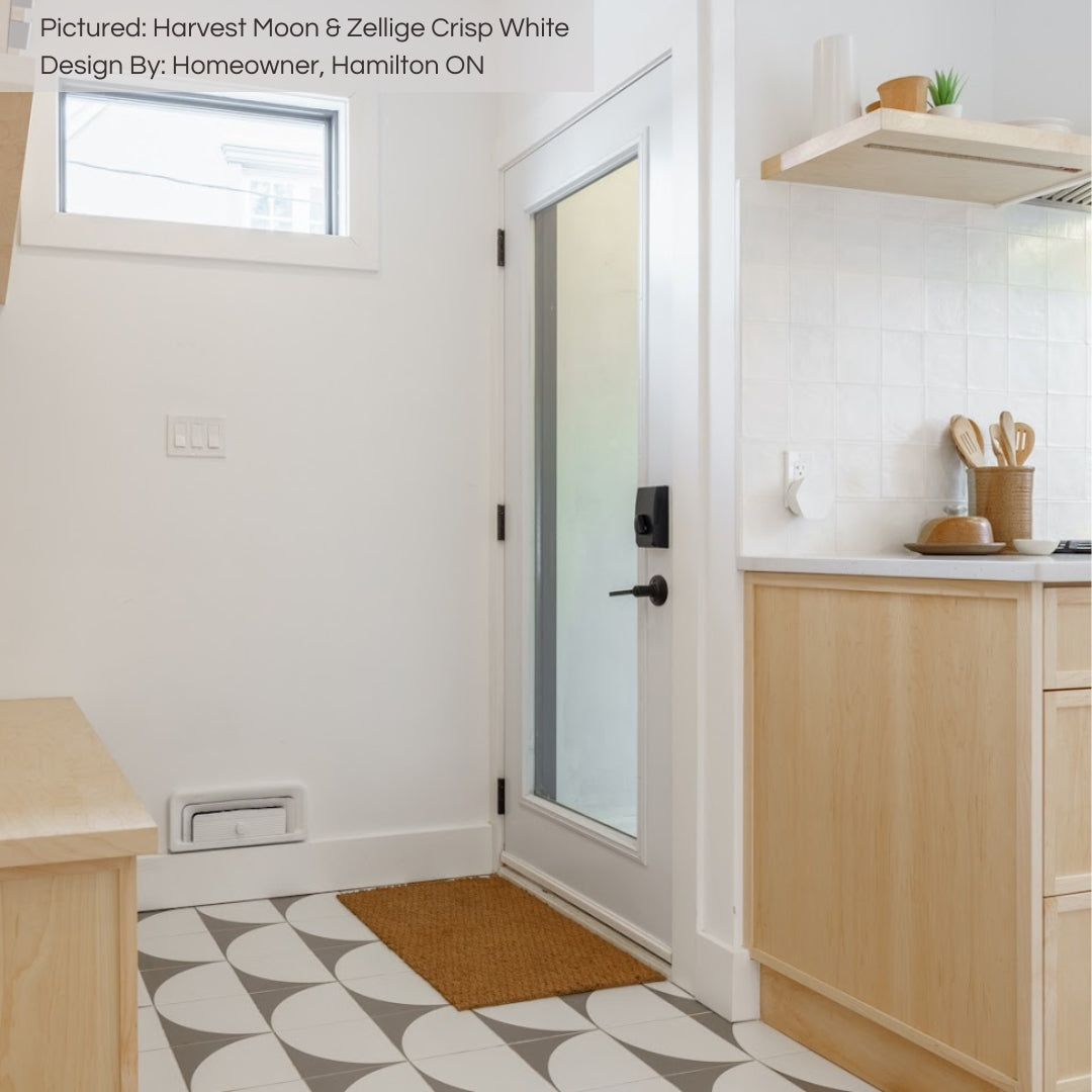 A modern white and light wood kitchen entryway. The tiles on the floor are a fun semicircle grey and white pattern called harvest moon. 