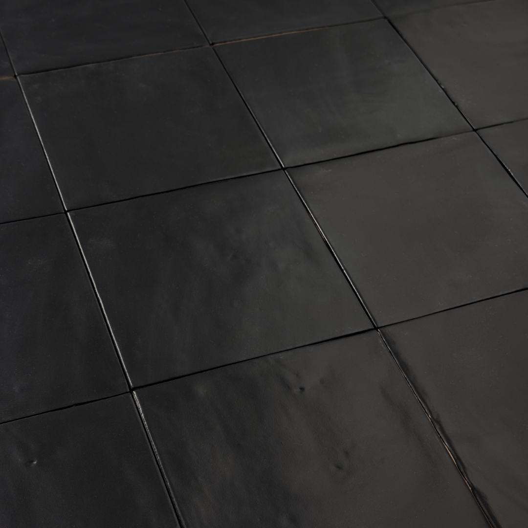 Angled close up view of a group of matte 5x5 textured carbon black tiles showing the textured edges. 