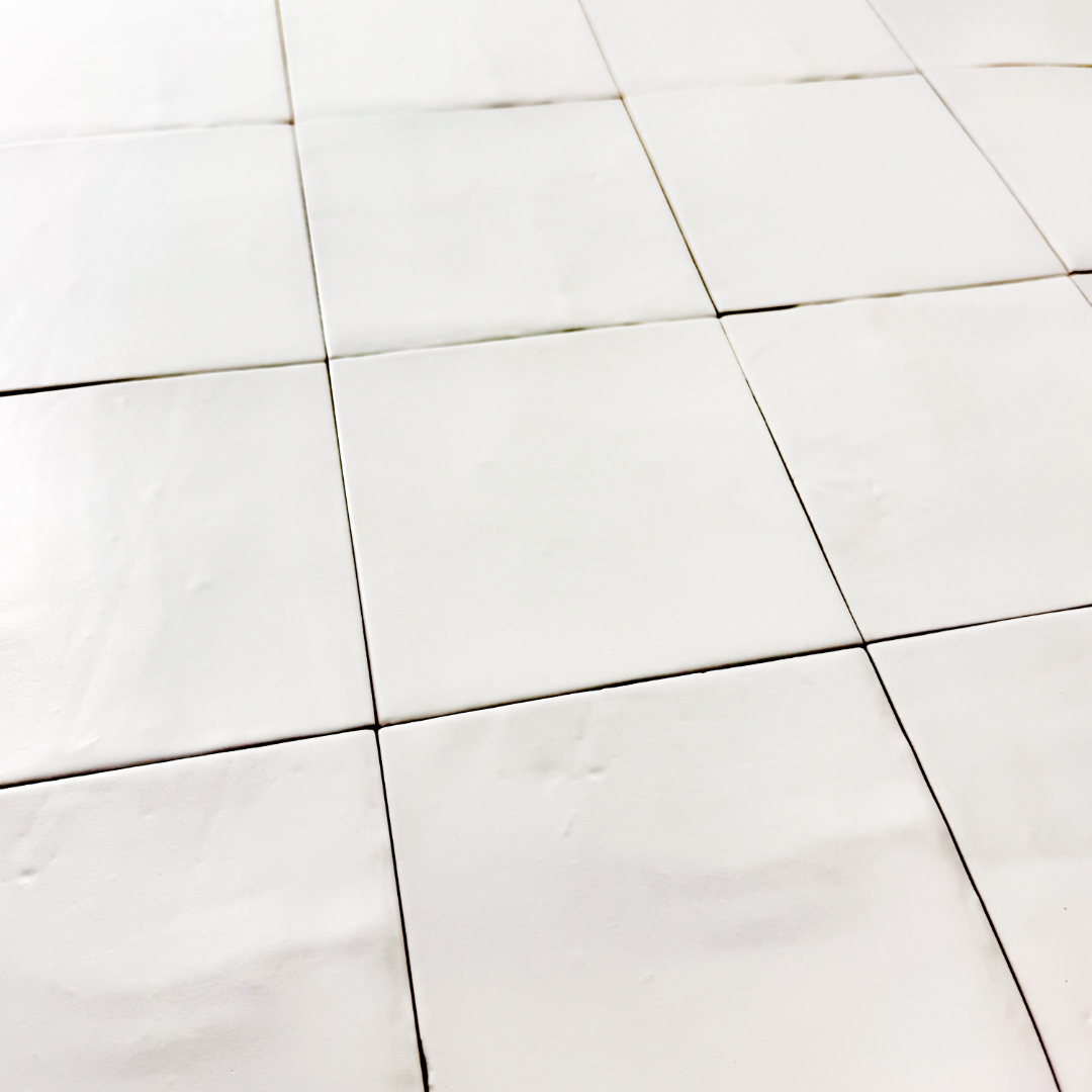 Angled close up view of a group of matte 5x5 textured powder white tiles showing the textured edges. 