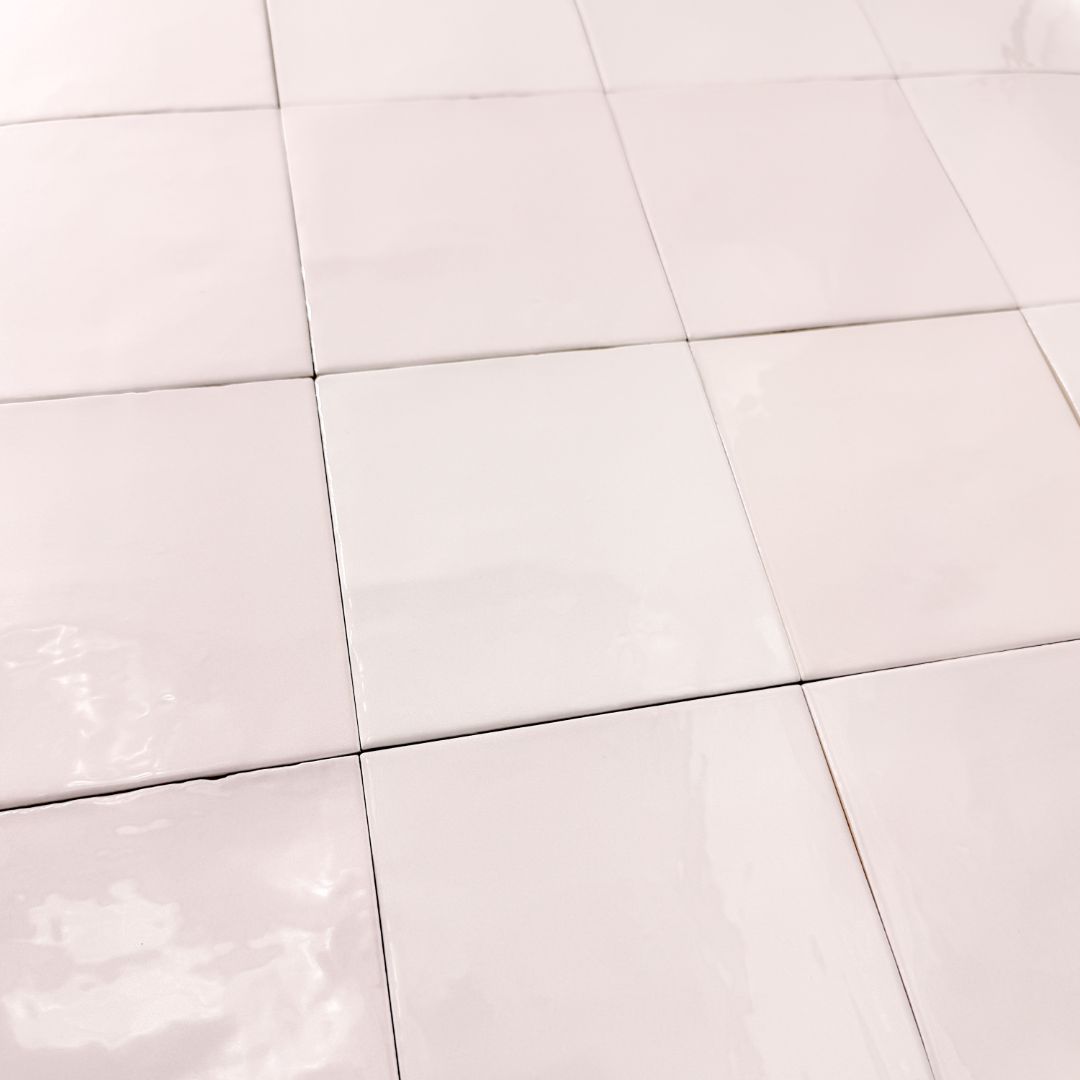 Angled close up view of a group of matte 5x5 textured light blush pink tiles showing the textured edges. 