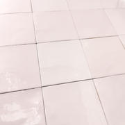 Angled close up view of a group of matte 5x5 textured light blush pink tiles showing the textured edges. 