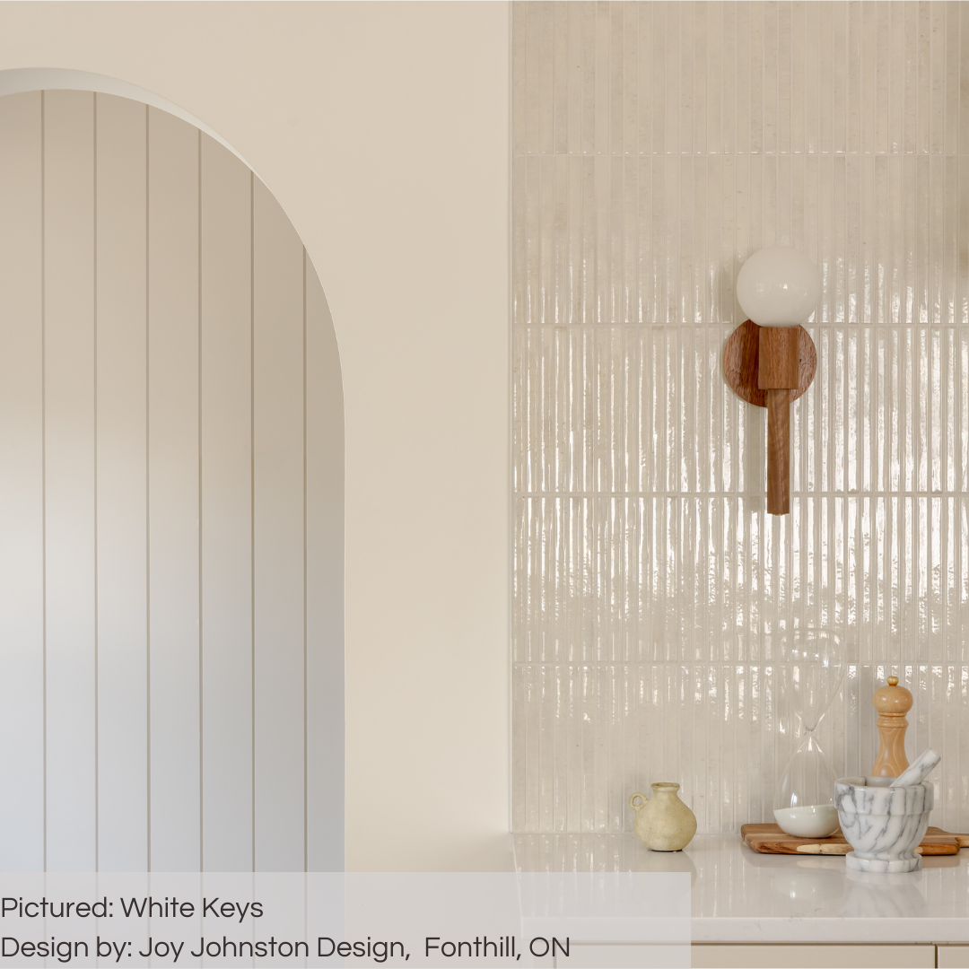 Close up on a  white kitchen wall with a wood look sconce and white 5x10 glossy fluted tiles. the tiles catch the light and look so luxurious. 