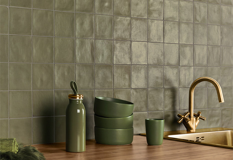 Close up of a kitchen backsplash. The 4x4 textured zellige tiles are olive kale green and match the stoneware dishes. the gold sink and wood countertop give this kitchen a vintage neutral vibe. 