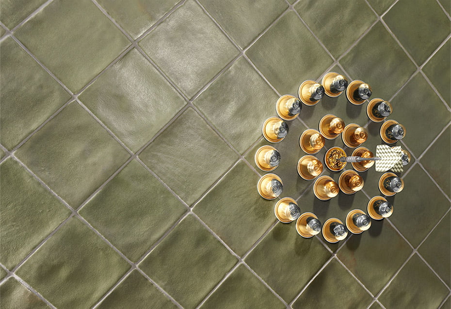 A tiled wall surface with 4x4 zellige kale olive green tiles installed in a diamond formation angle. 
