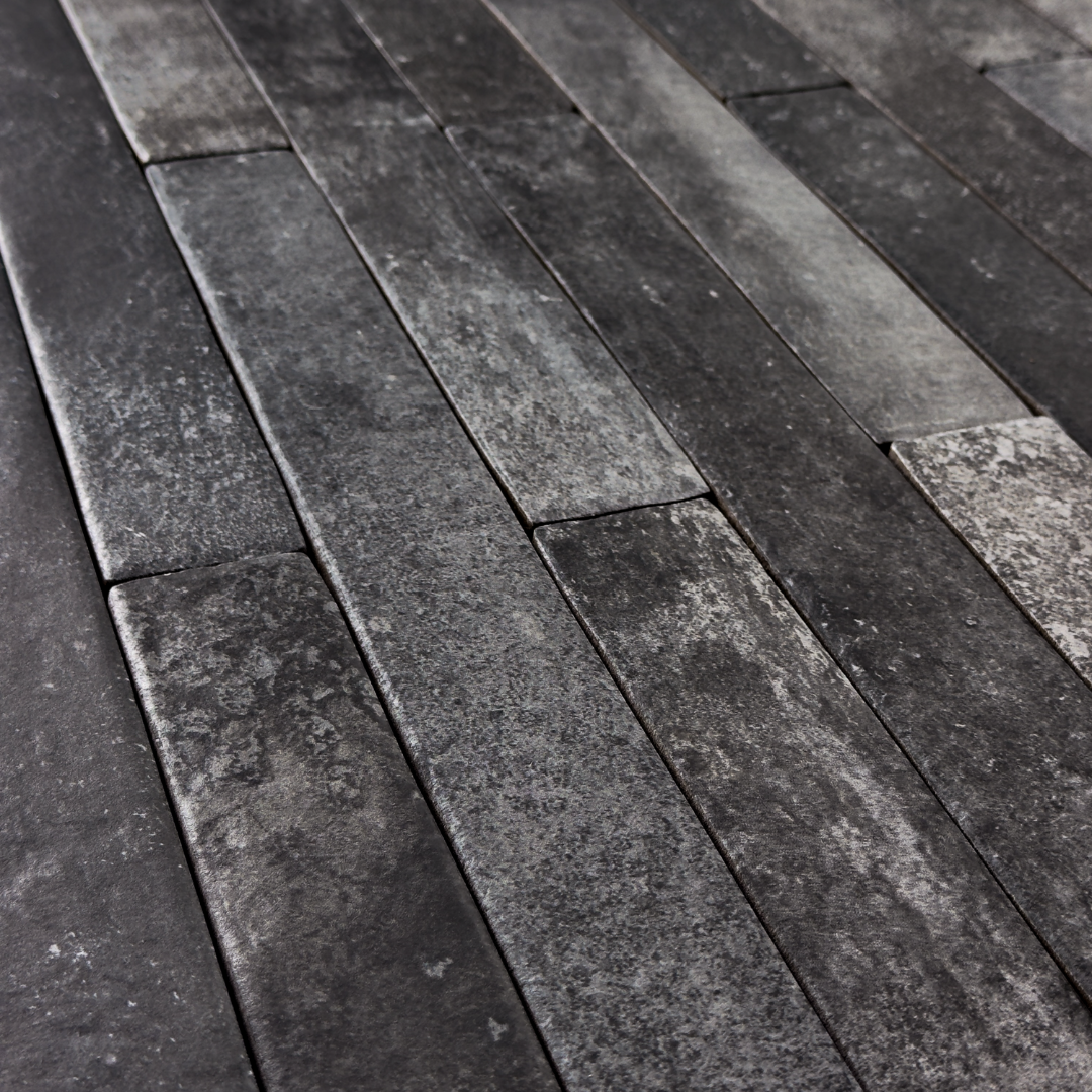 Angled close up view of charcoal black 2x18 brick look tiles laid in a vertical brick pattern. Showing colour variance, texture and the finish. 