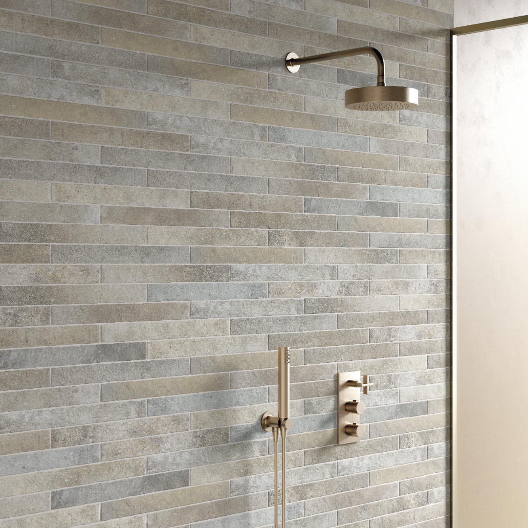 A modern shower with gold hardware, the shower tile is greige 2x18 brick look tiles in a horizontal brick pattern with some colour variation and texture. 