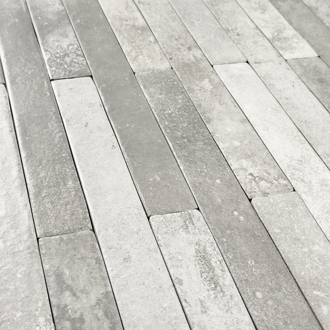 Angled close up view of grey 2x18 brick look tiles in a vertical brick pattern. Showing the texture and finish of the tiles.