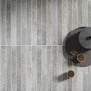 A close up of a tiled table surface. The tiles are 2x18 grey brick look tiles with colour variation, light texture and installed in a modern stacked pattern. 