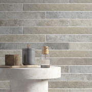 A close up view of a wall or backsplash, the tile is greige 2x18 brick look tiles in a horizontal brick pattern with some colour variation and texture. 