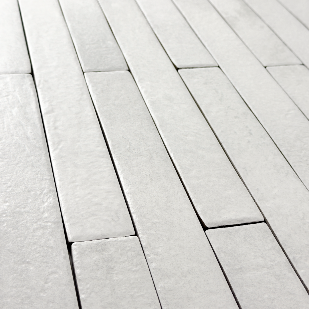 Angled view of white 2x18 brick look tiles in a vertical brick pattern. Showing the texture and finish of the tiles.