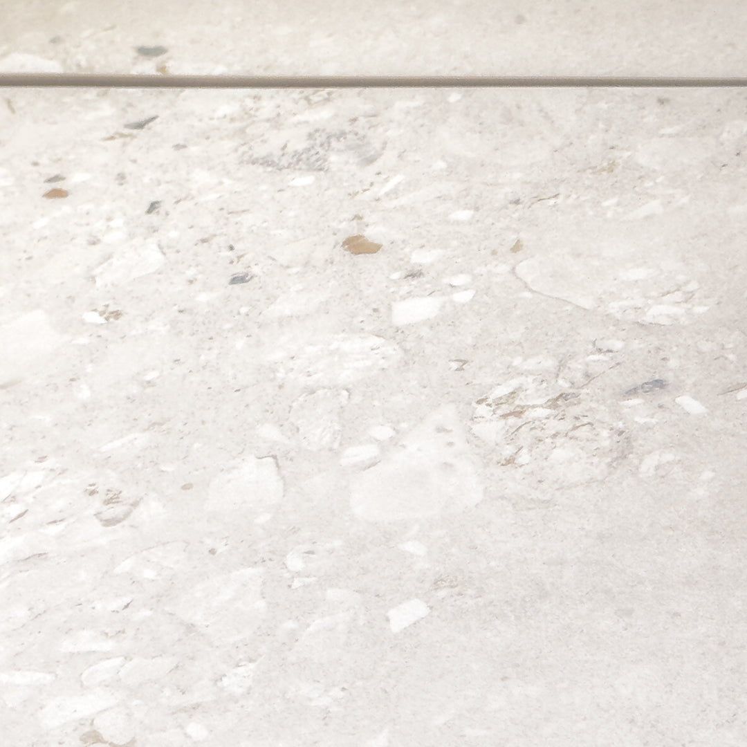 Angled close up of two 36x36 cement terrazzo look tiles called oasis light they have a light stone base with light flecks in matte finish. 
