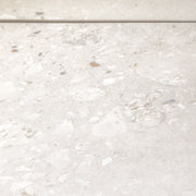 Angled close up of two 36x36 cement terrazzo look tiles called oasis light they have a light stone base with light flecks in matte finish. 